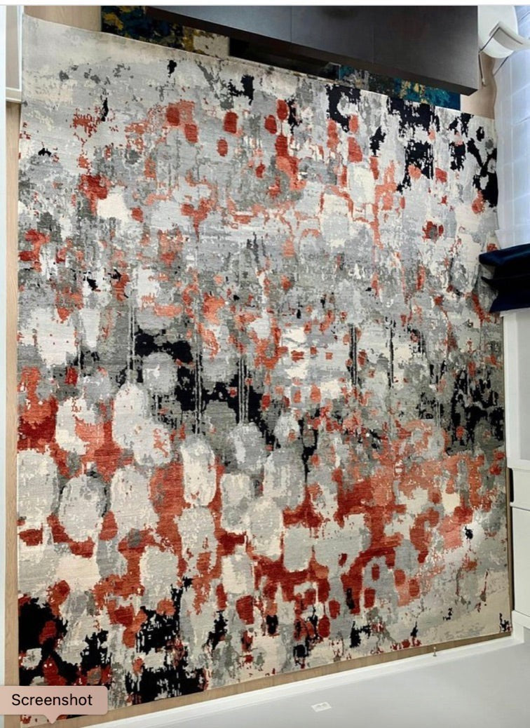 Grand Expressions Gallery and Home Store custom wool rug with abstract rusty-red, grey, cream, and black pattern.