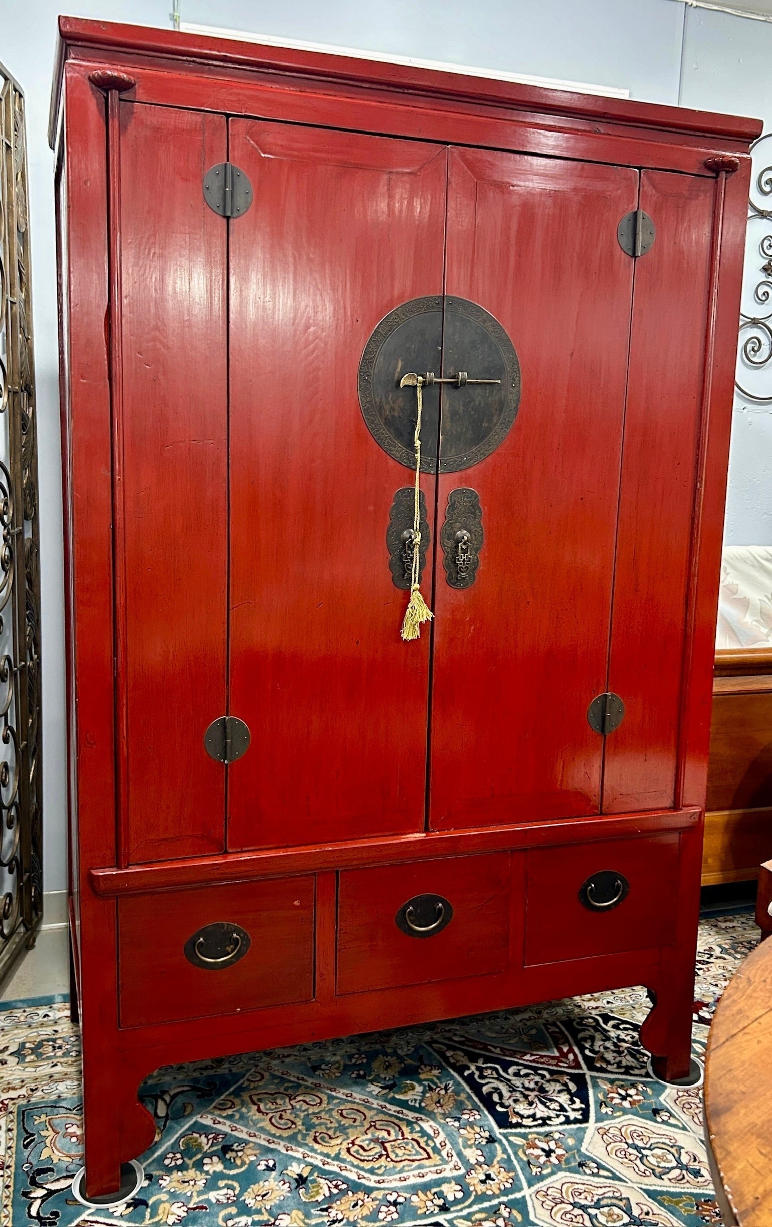 Grand Expressions Gallery and Home Store red lacquer elm wood armoire with brass hardware and three base drawers.