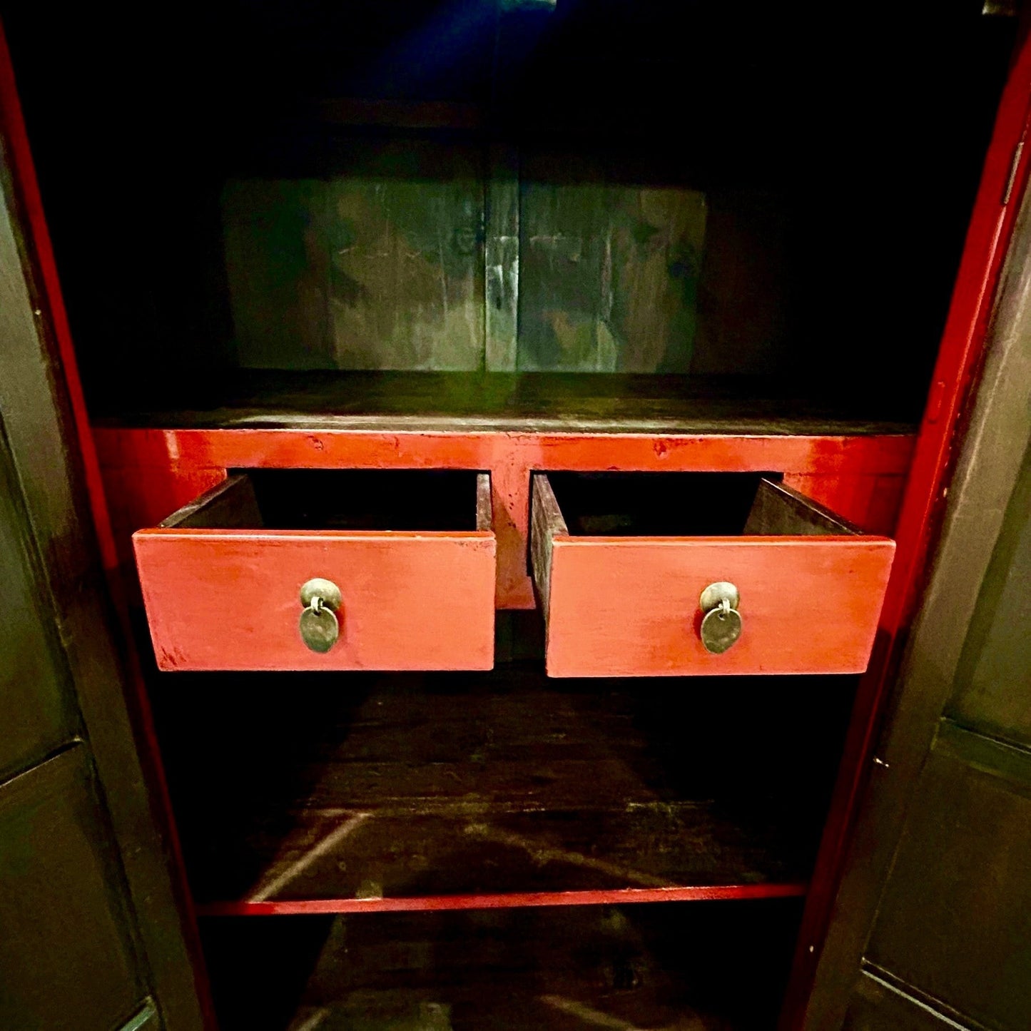 Interior view of a Grand Expressions Gallery and Home Store red lacquer armoire with two small drawers and shelving.
