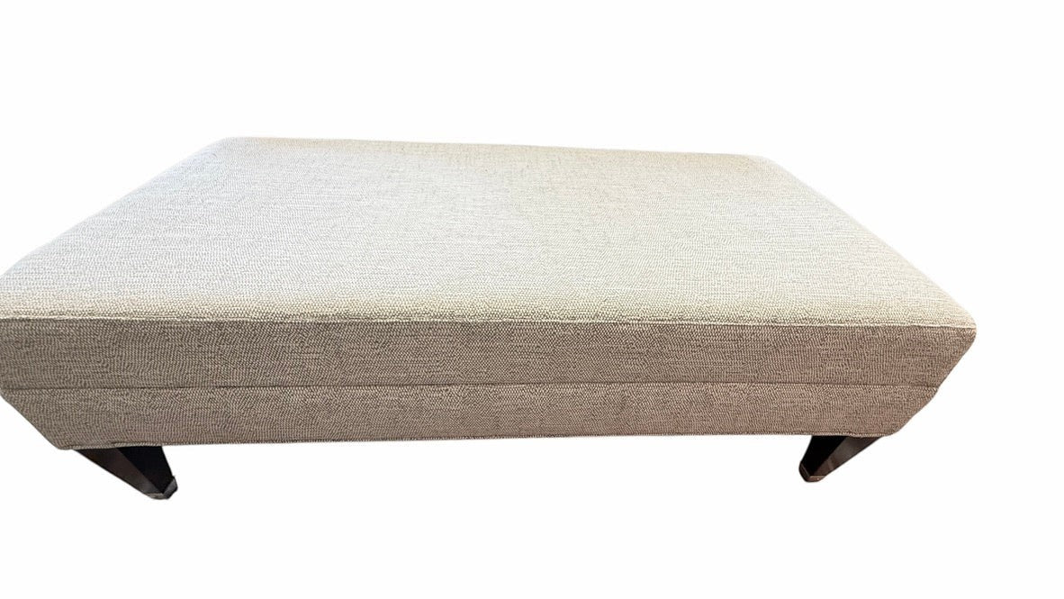 Grand Expressions Gallery and Home Store Wesley Hall ottoman in light grey-beige performance fabric with dark legs.